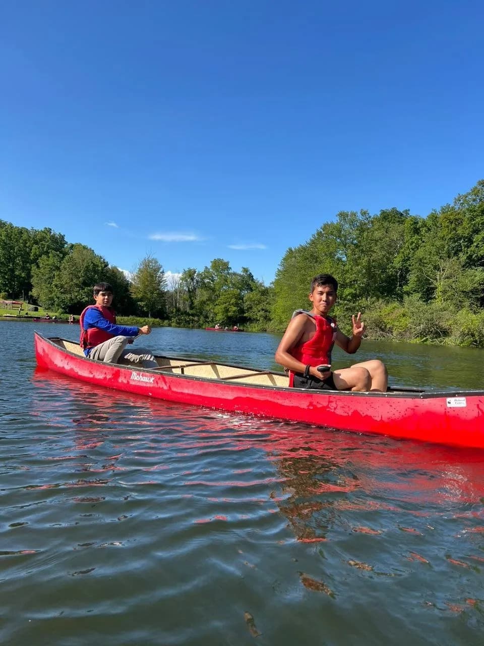 Two campers paddling a red canoe on the lake